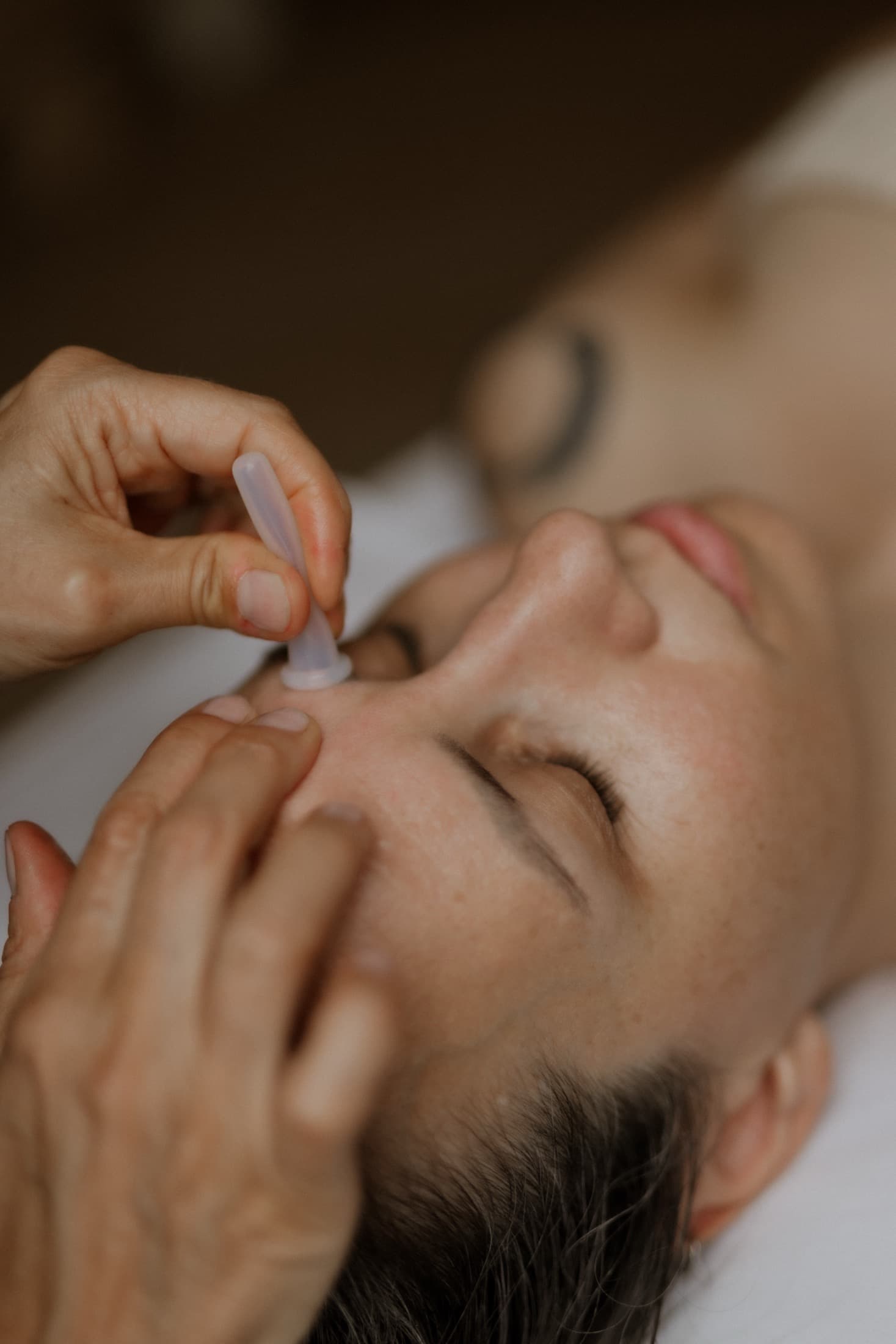 Close-up van een kleine siliconen cup op het voorhoofd tijdens een facial cupping-behandeling