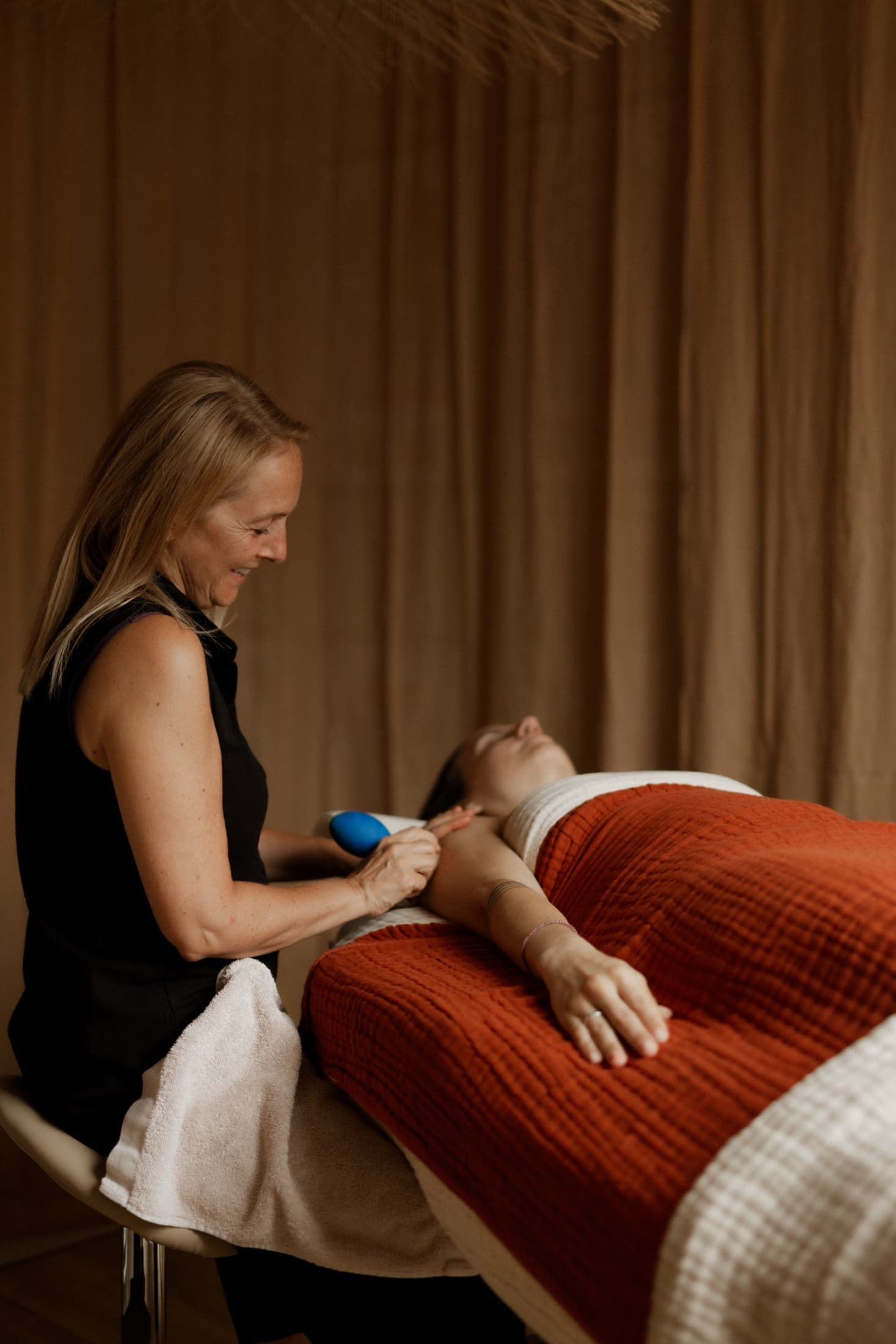 Sophie behandelt een cliënte met cupping, warm licht door het gordijn